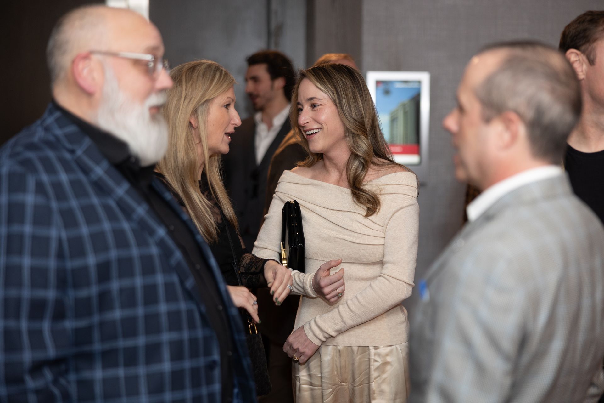 A group of people are standing around talking to each other in a room.