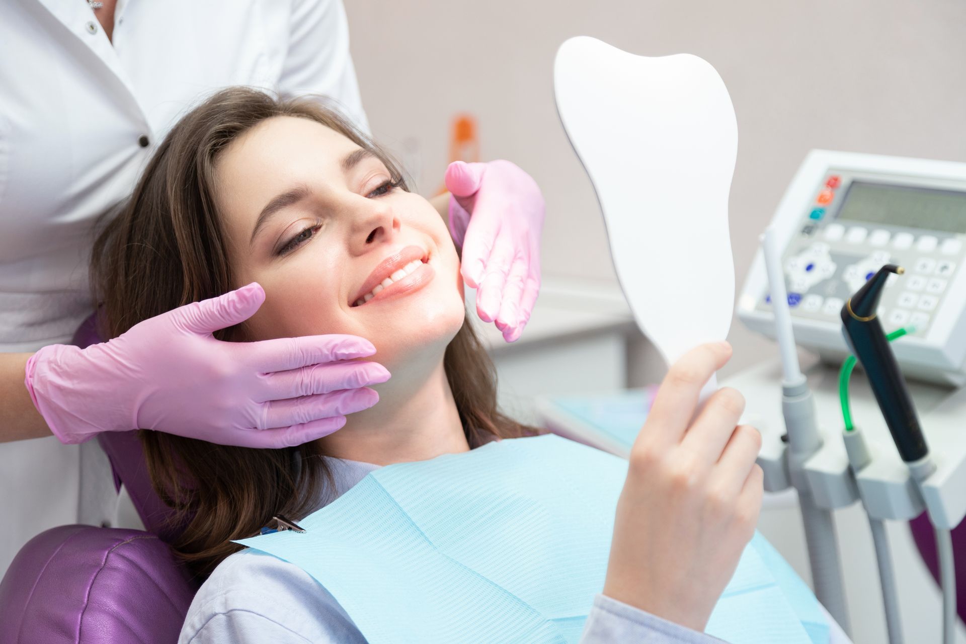 A woman is looking at her teeth in a mirror.
