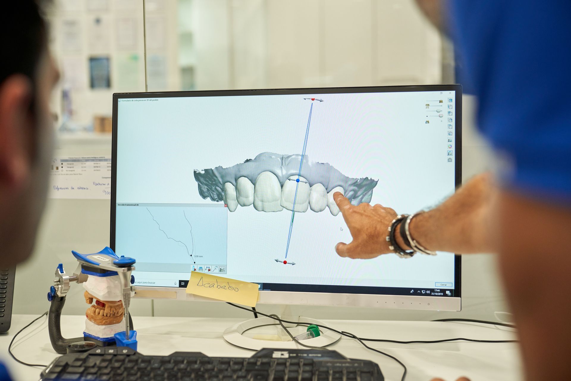 A prosthodontist is examining a denture in a computer.