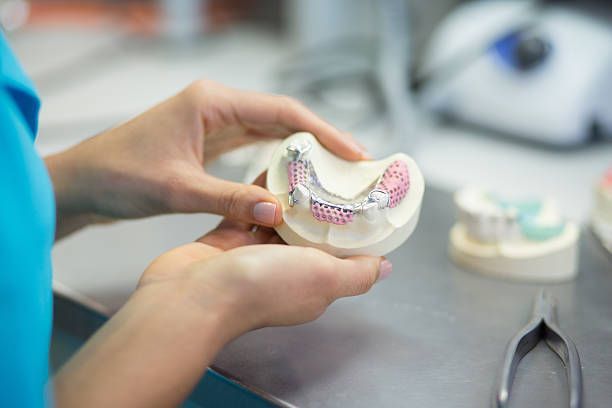 A close-up of a dentist working on a prosthodontic lower jaw model.