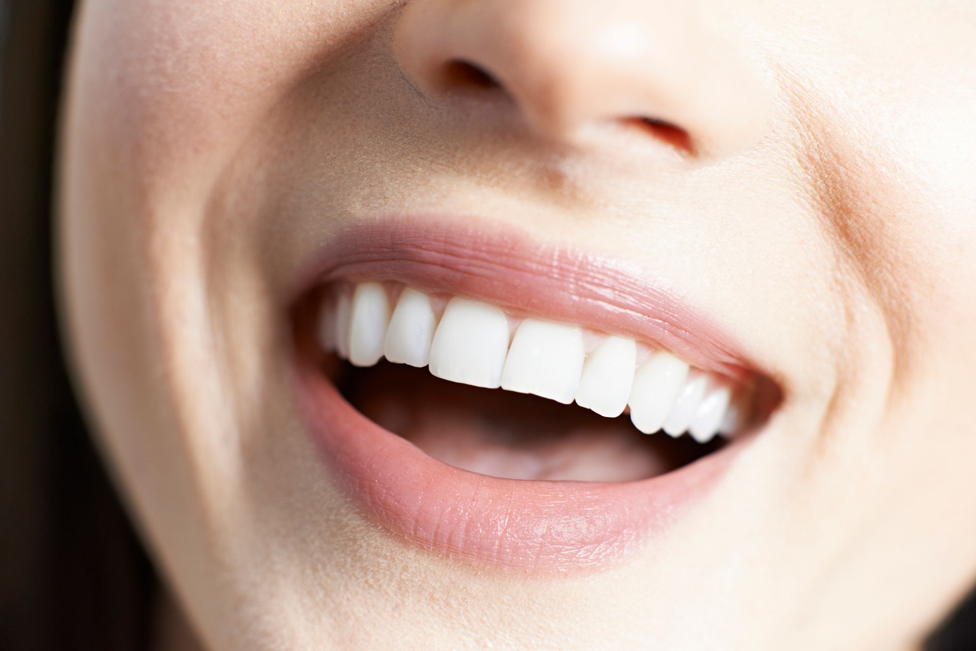 Close-up of woman smiling with straight white teeth and perfect dental health 