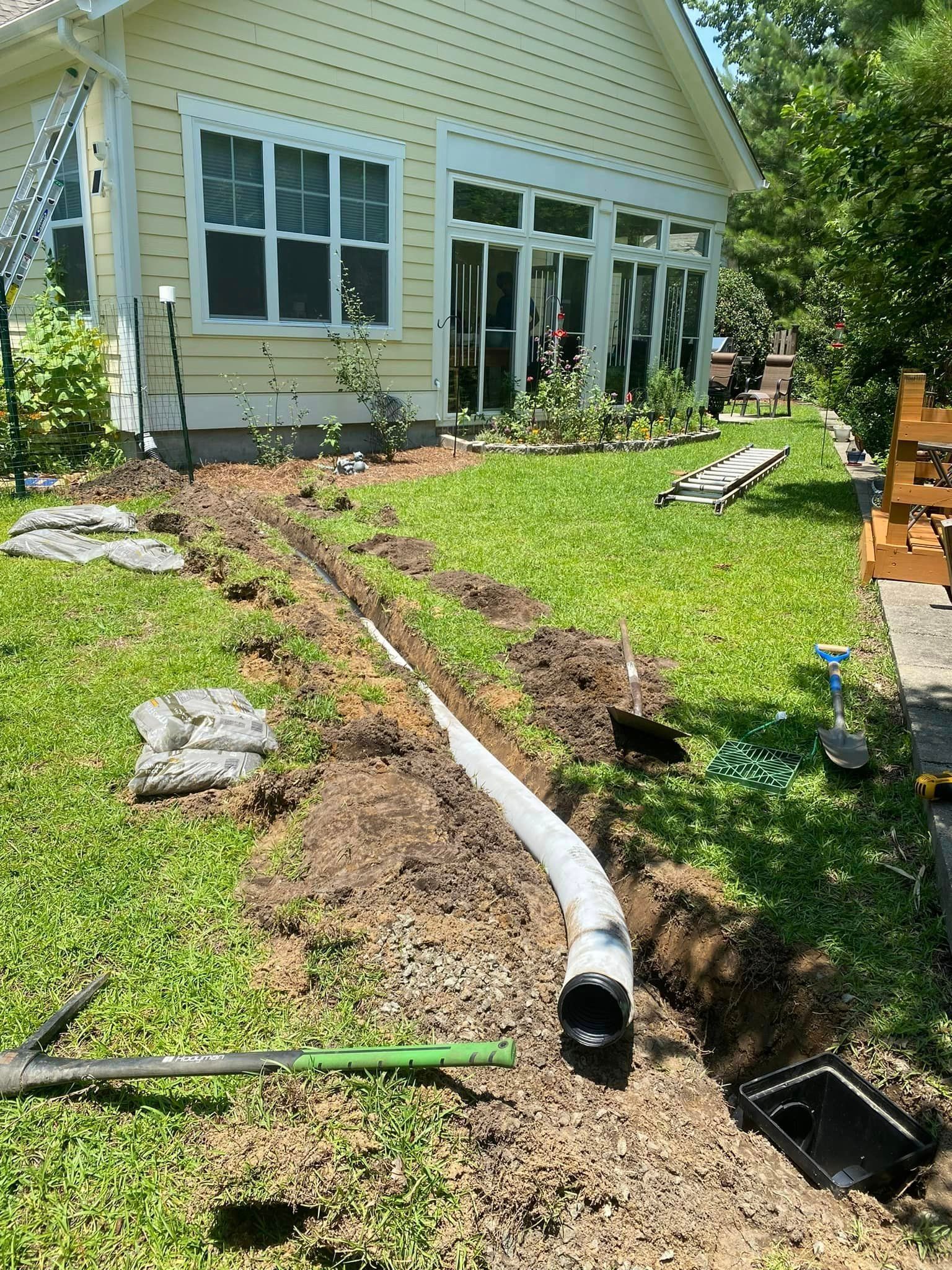 A drain pipe is being installed in the backyard of a house.