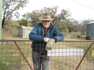 old man standing behind a fence