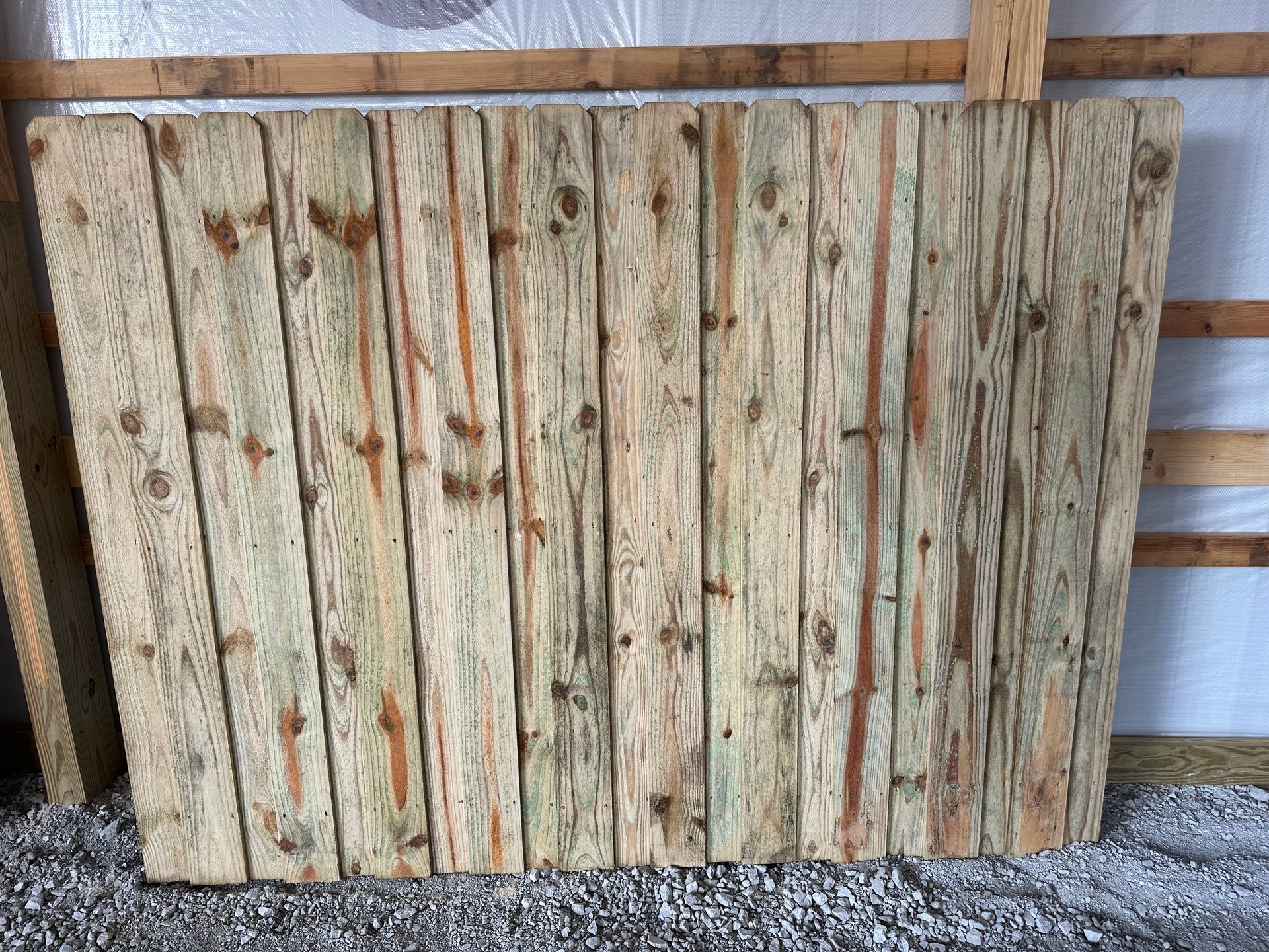 A wooden fence is in the backyard of a house.