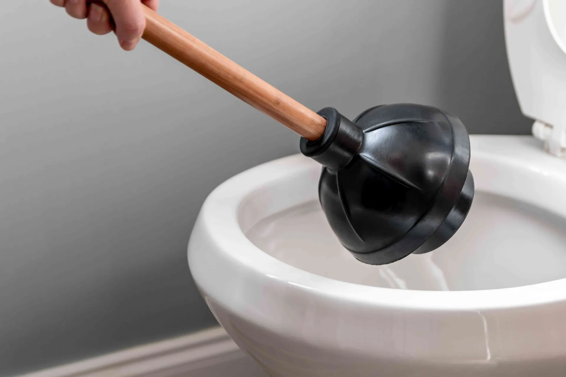 A plunger coming out of a toilet