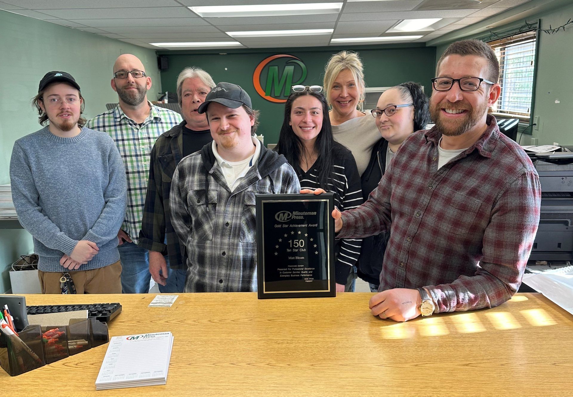 A group of people are standing around a table holding a plaque.