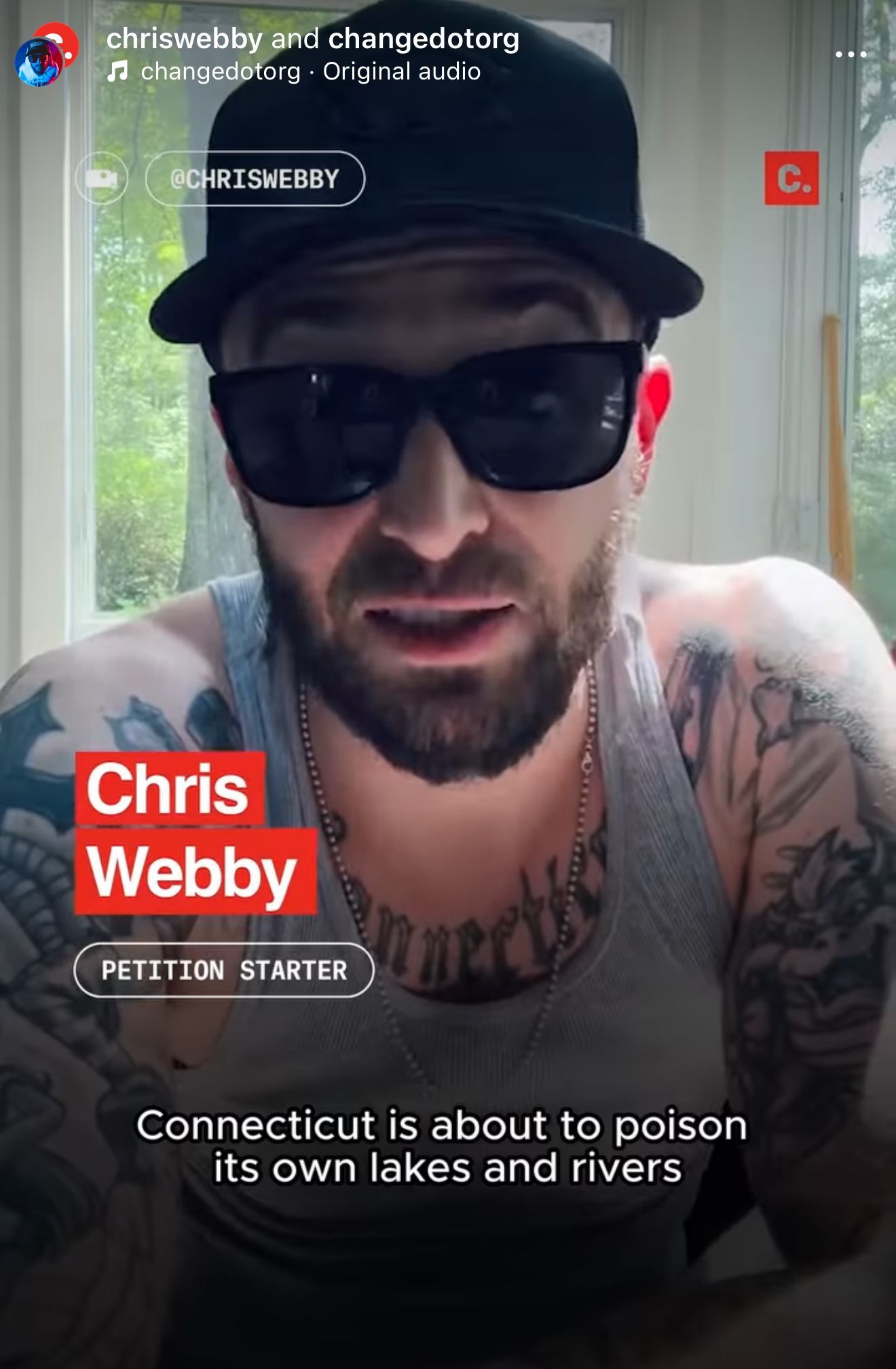 A man with a beard and tattoos is wearing sunglasses and a hat.