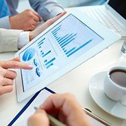 a group of people are sitting at a table looking at a tablet computer .