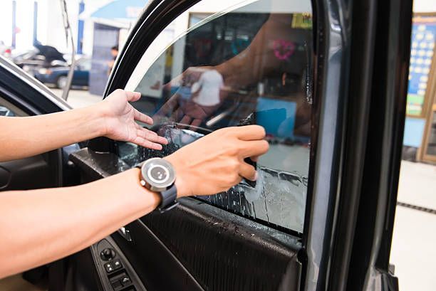 A person is applying tinted glass to a car window.