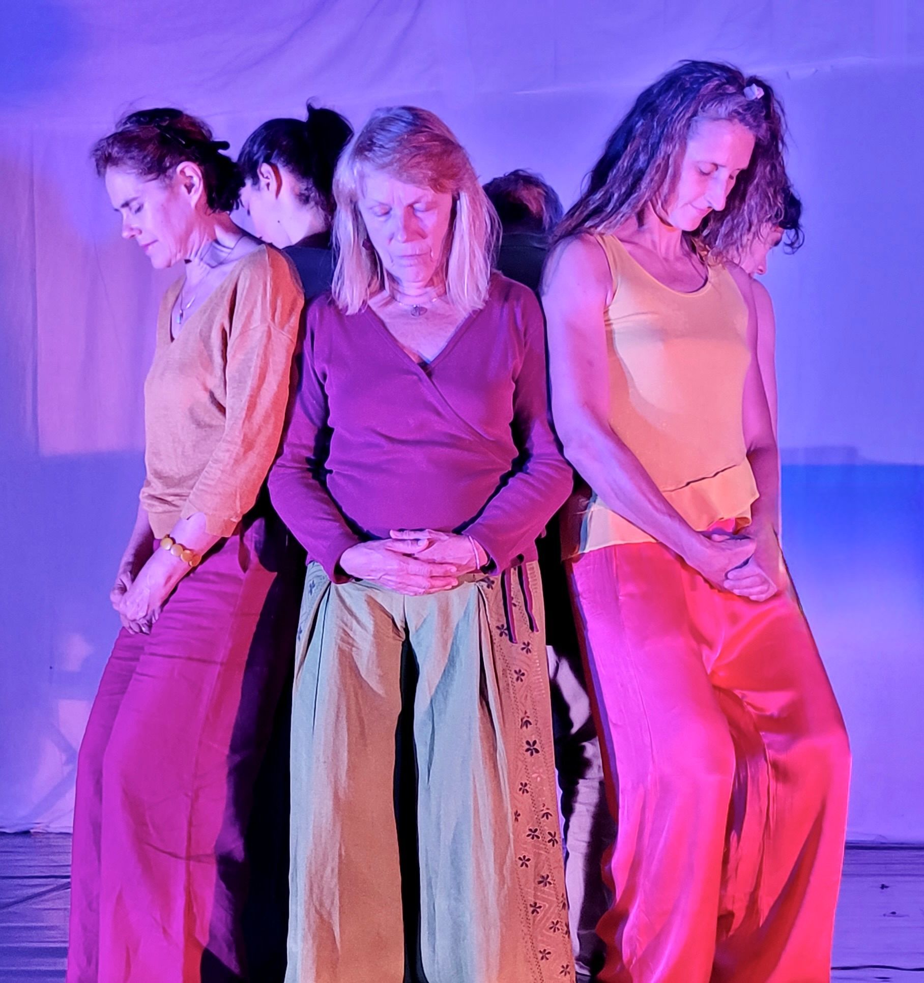 Une femme danse sur scène vêtue d'une robe bleue. Éclairage rose et violet.