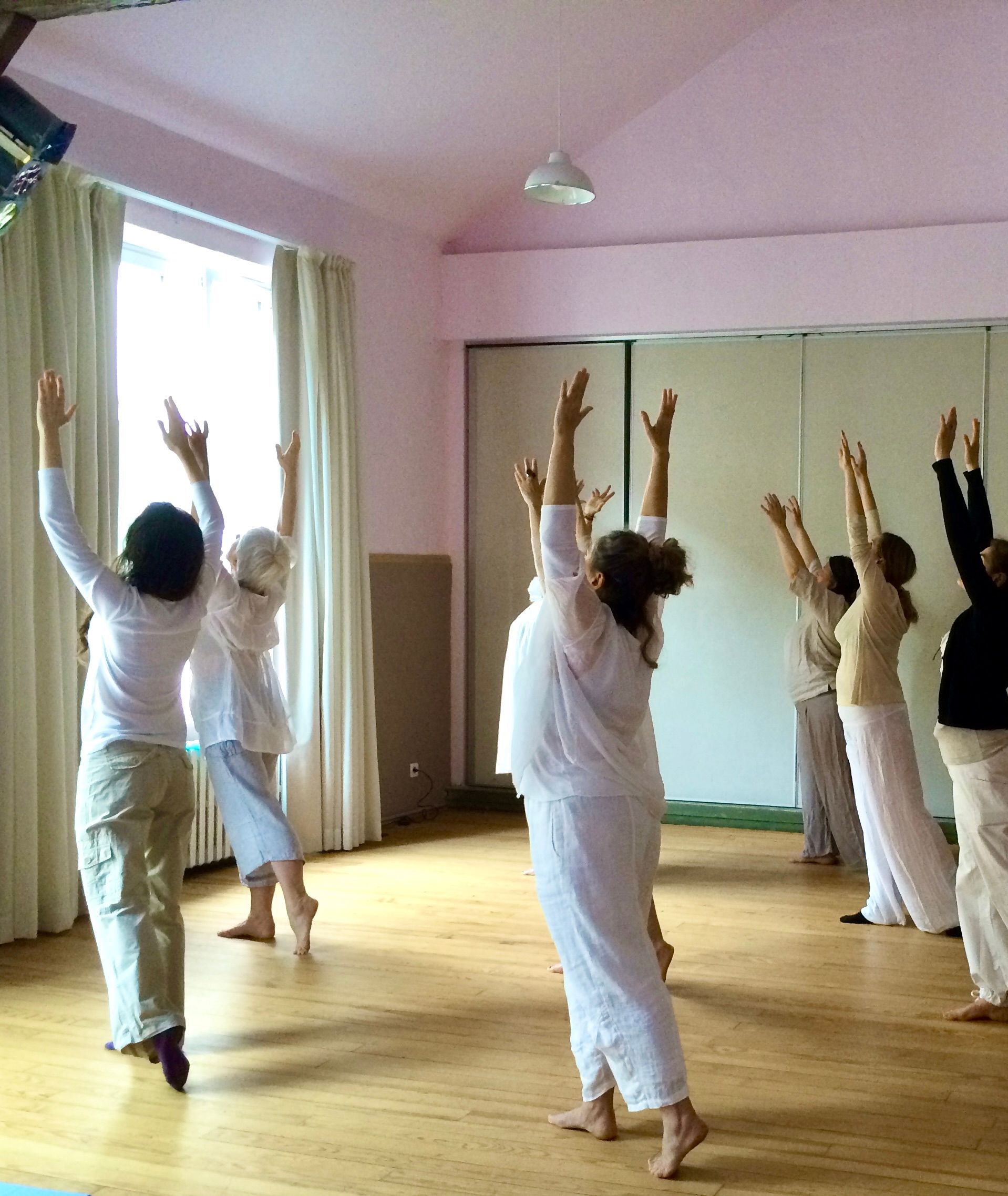 Un danseur vêtu de blanc et de violet se produit sur une scène réfléchissante, les bras tendus.