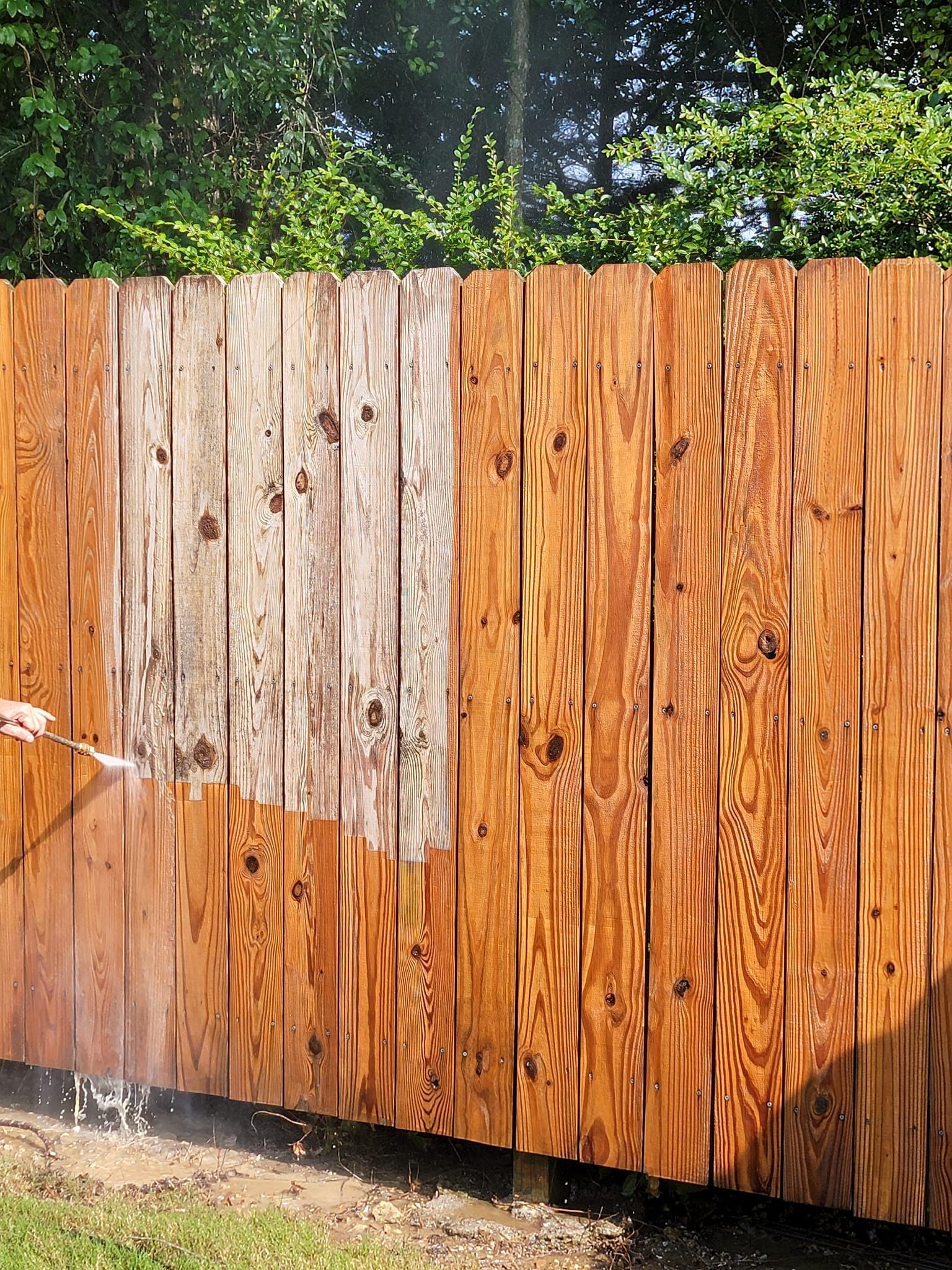 a person is cleaning a wooden fence with a high pressure washer .