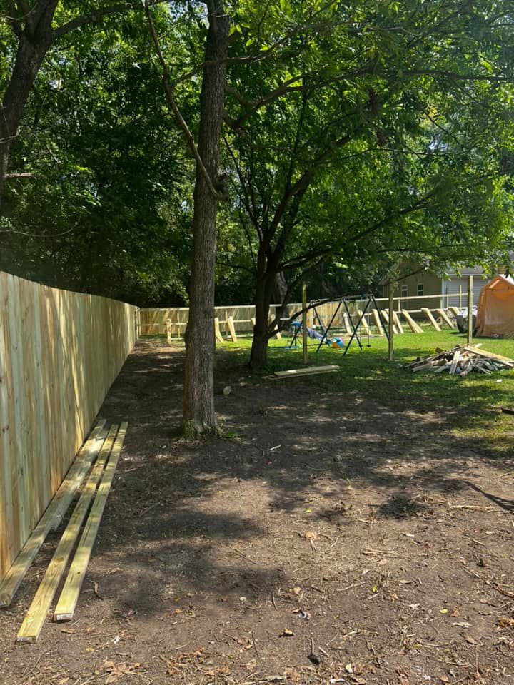 a wooden fence is being built in a yard surrounded by trees .