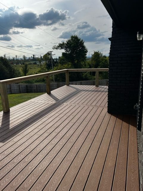 a wooden deck with a wooden railing and a view of a field