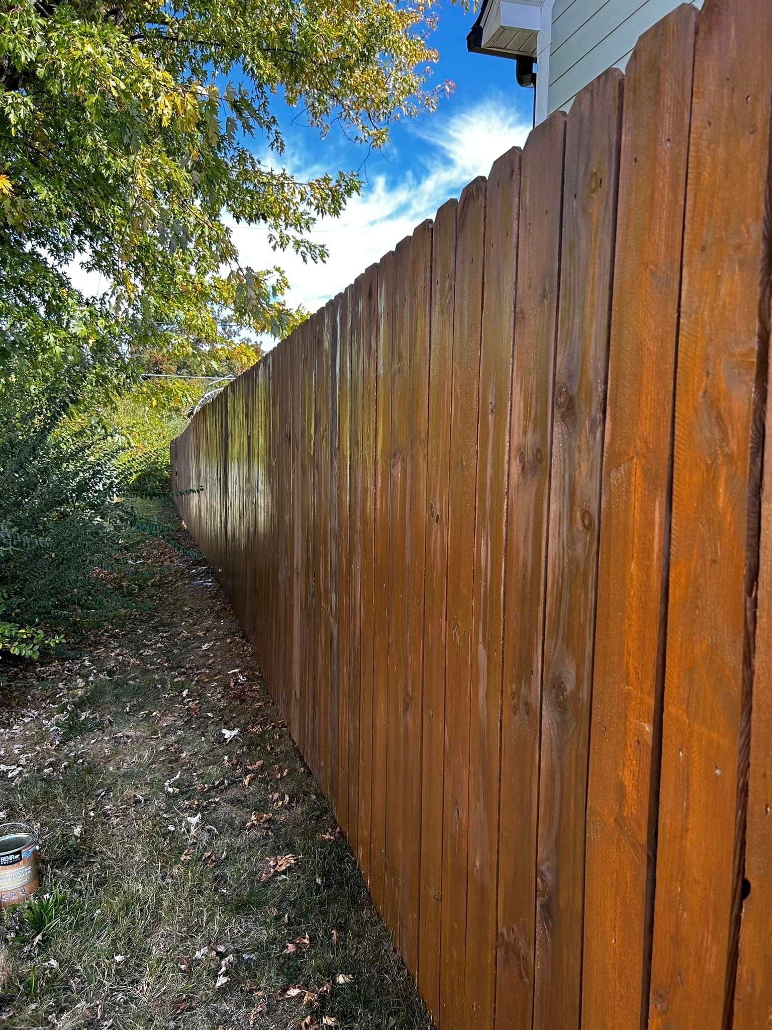 a wooden fence is surrounded by trees in a backyard .
