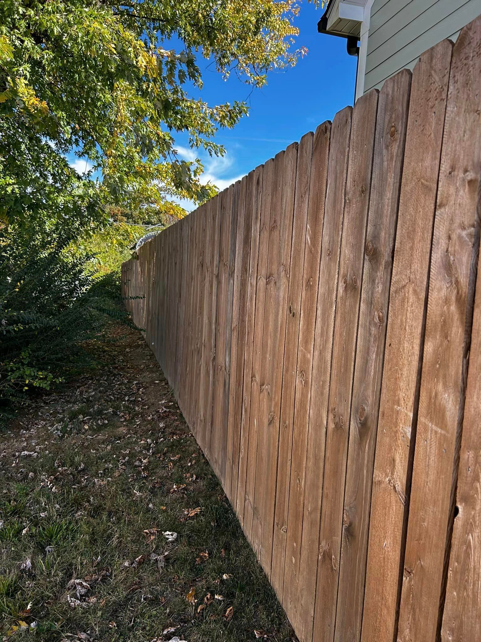 a wooden fence is surrounded by trees and grass in front of a house .