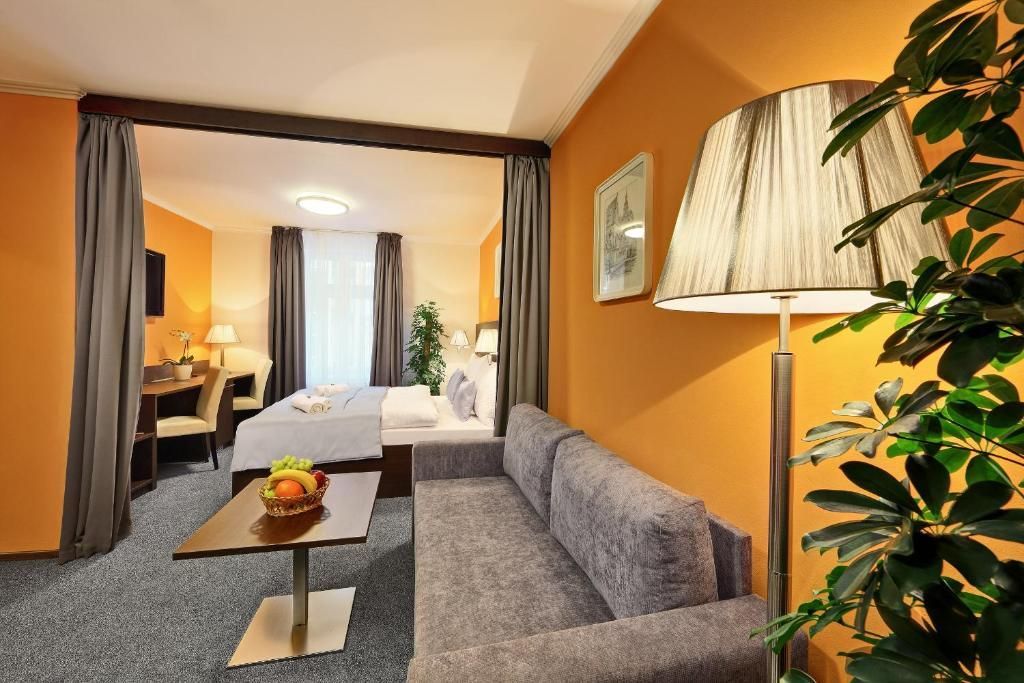 A hotel room with a couch , table , lamp and bed.