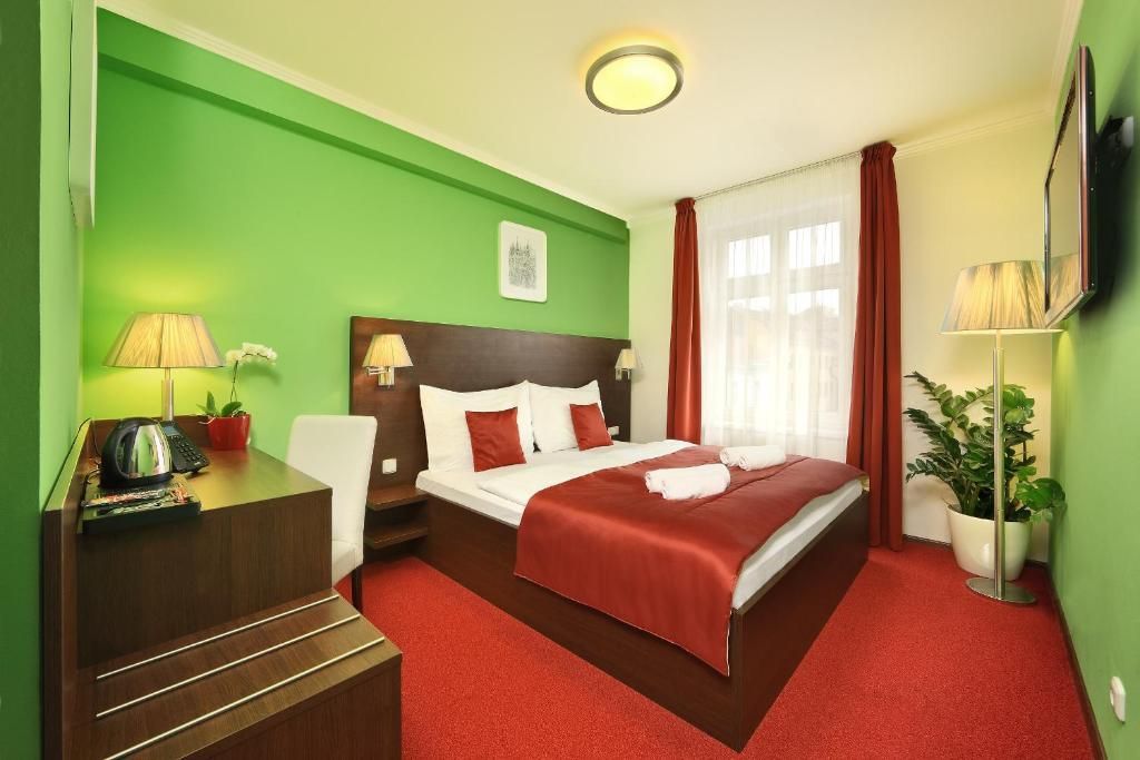 A hotel room with a large bed and green walls