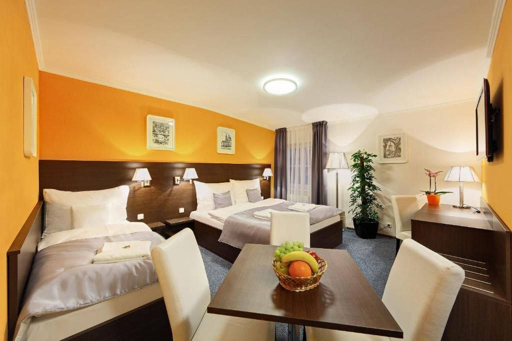 A hotel room with two beds and a table with a bowl of fruit on it