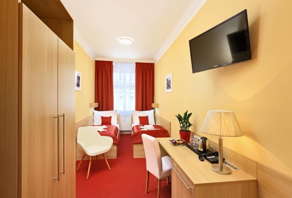 A hotel room with two beds , a desk and a flat screen tv.