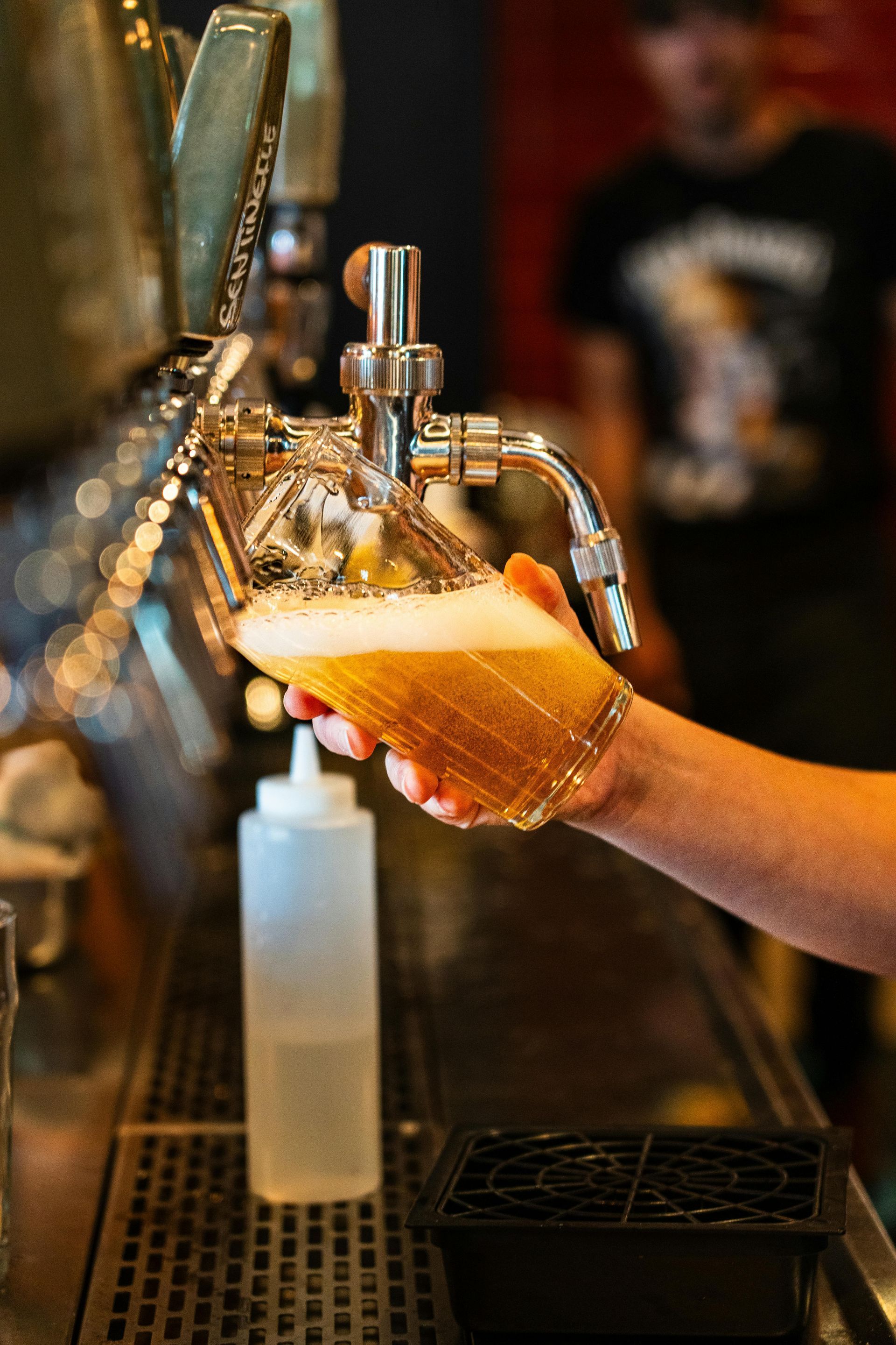 A person is pouring beer from a tap into a glass.