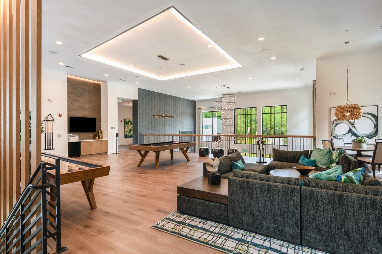 Spacious modern community lounge with sectional sofa, pool table, and large windows.