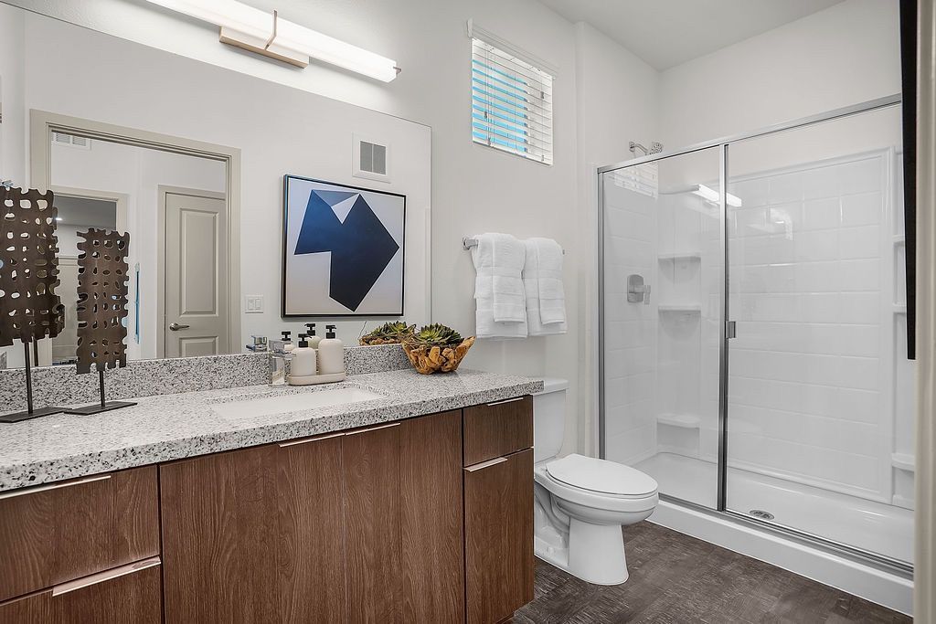 Bathroom with a single-sink vanity, granite countertop, glass-enclosed shower, and toilet.