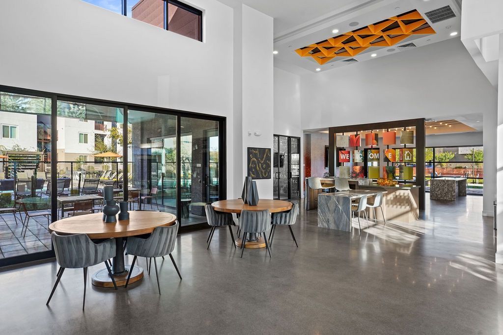 Modern apartment community lobby with round tables, chairs, and a reception desk.