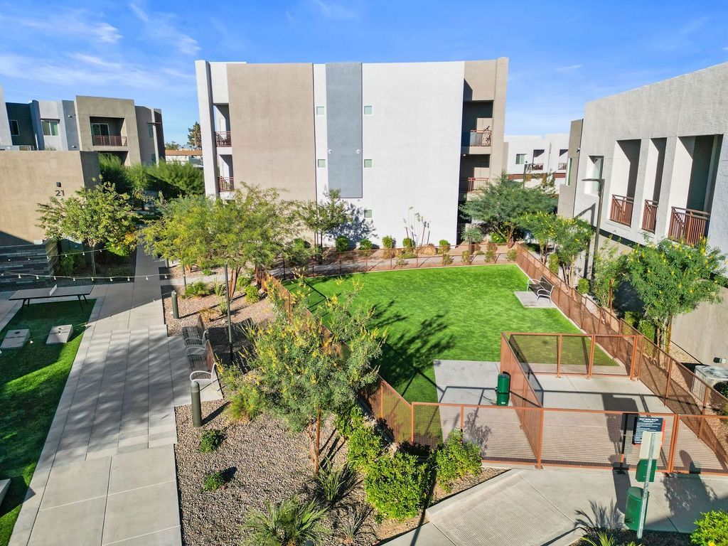 Aerial view of a modern apartment community courtyard with lawn, walkways, and surrounding buildings.