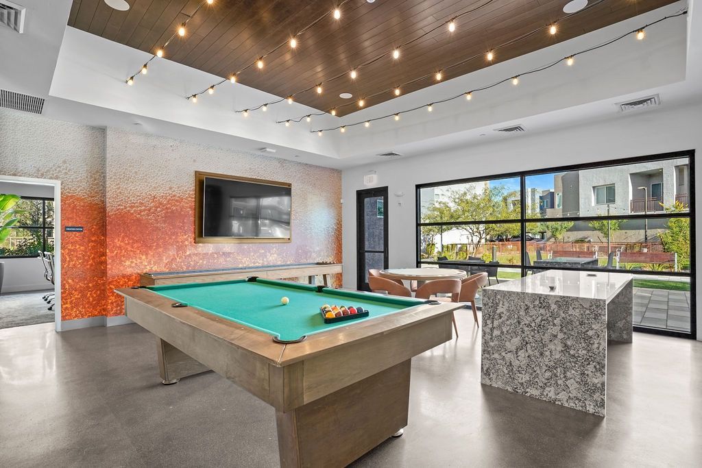 Indoor community recreation room featuring a pool table, TV, and string lights.