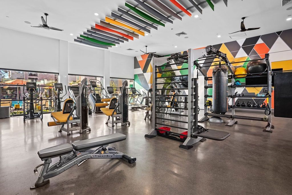 Bright on-site fitness center with cardio machines, weight racks, and a punching bag.