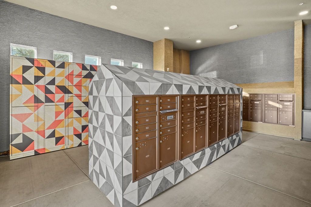 Indoor community mailroom with geometric-patterned walls and a row of brown mailboxes.