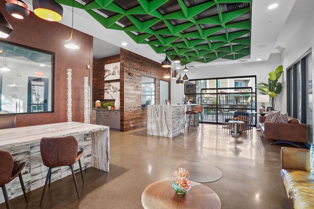 Interior of a modern apartment community lounge with a green geometric ceiling and seating areas.