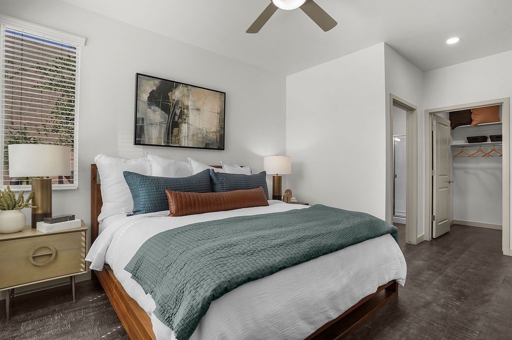Bedroom in apartment with bed, teal bedding, two nightstands, and an open closet.
