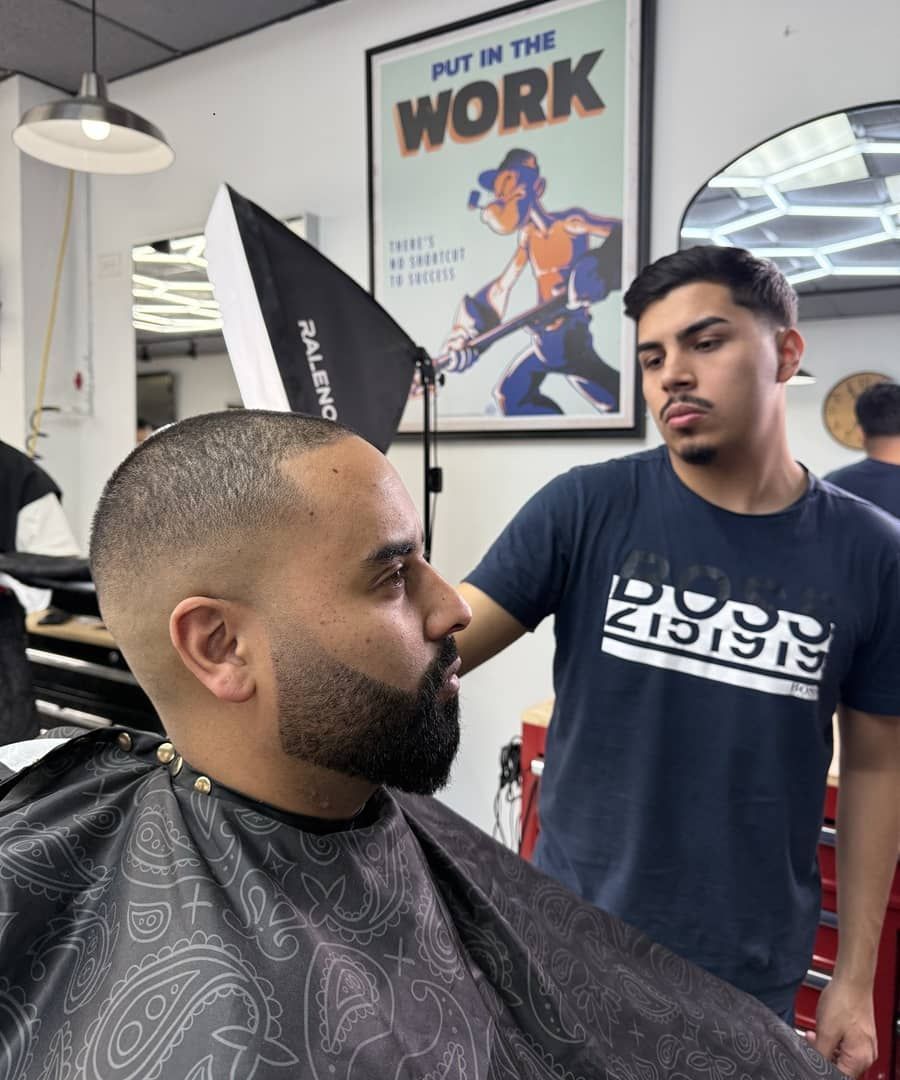 A man is getting his hair cut in front of a poster that says put in the work