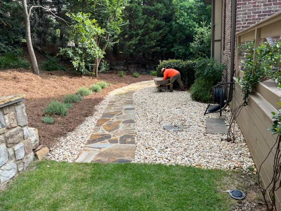 A man is working on a stone walkway in a backyard.