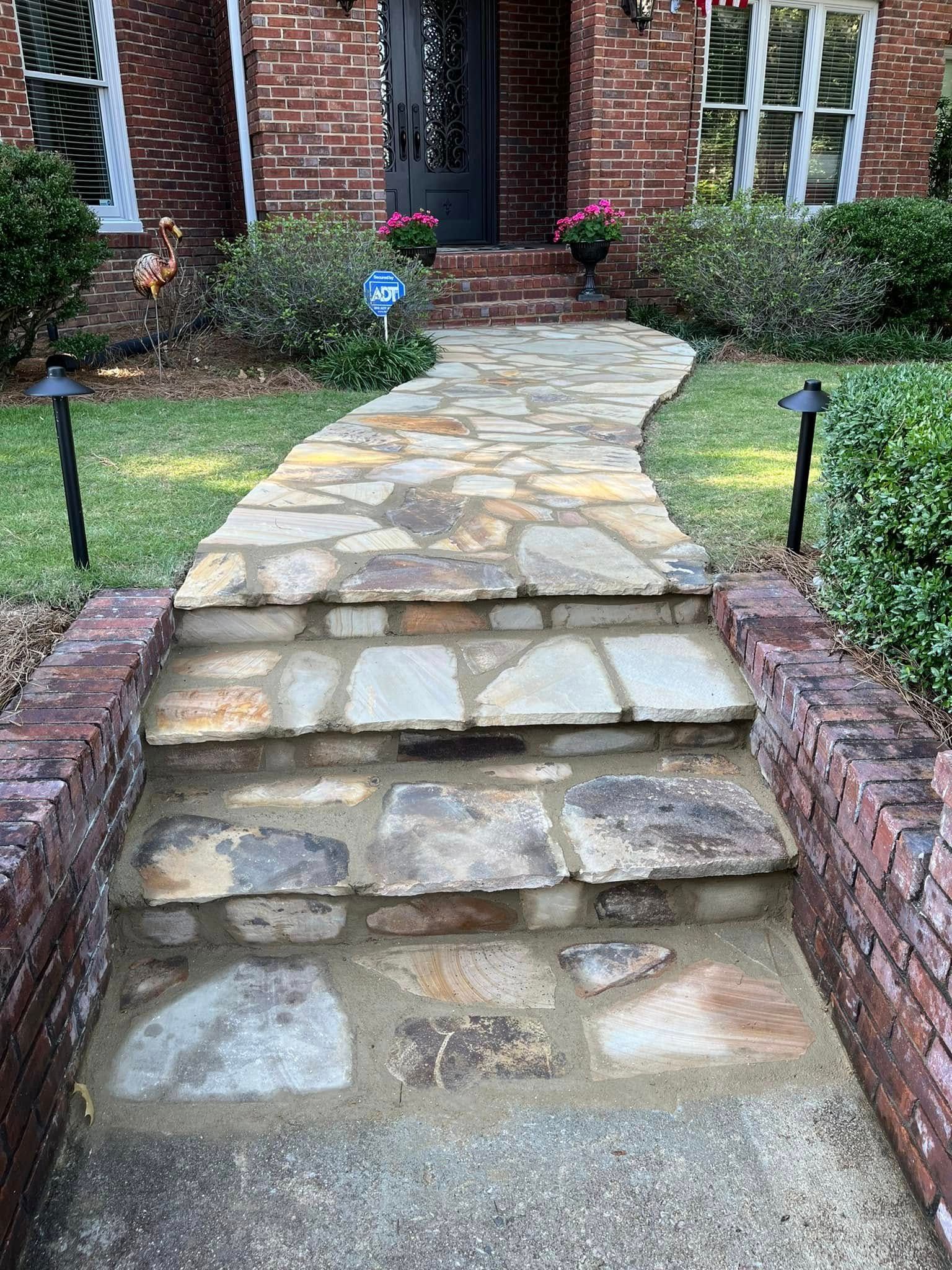 A stone walkway leading to the front door of a brick house.