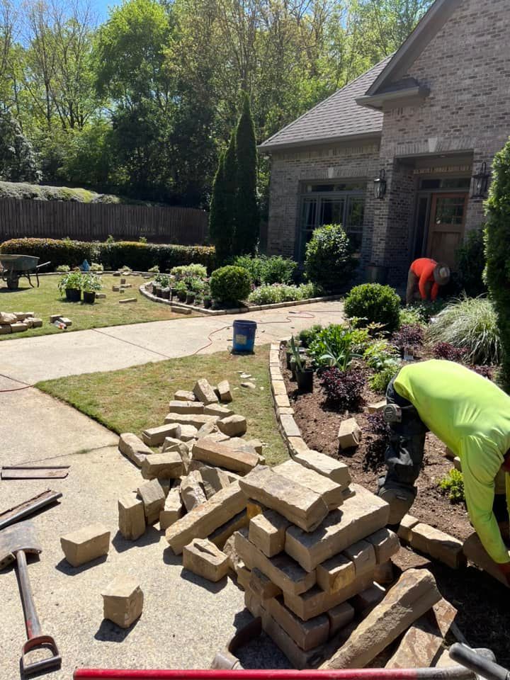 A man is working on a brick walkway in front of a house.