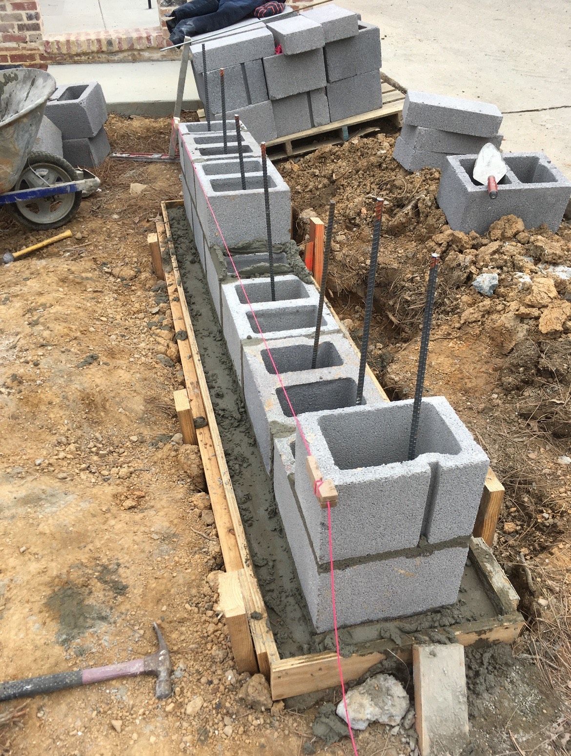 A row of concrete blocks are being built in the dirt.