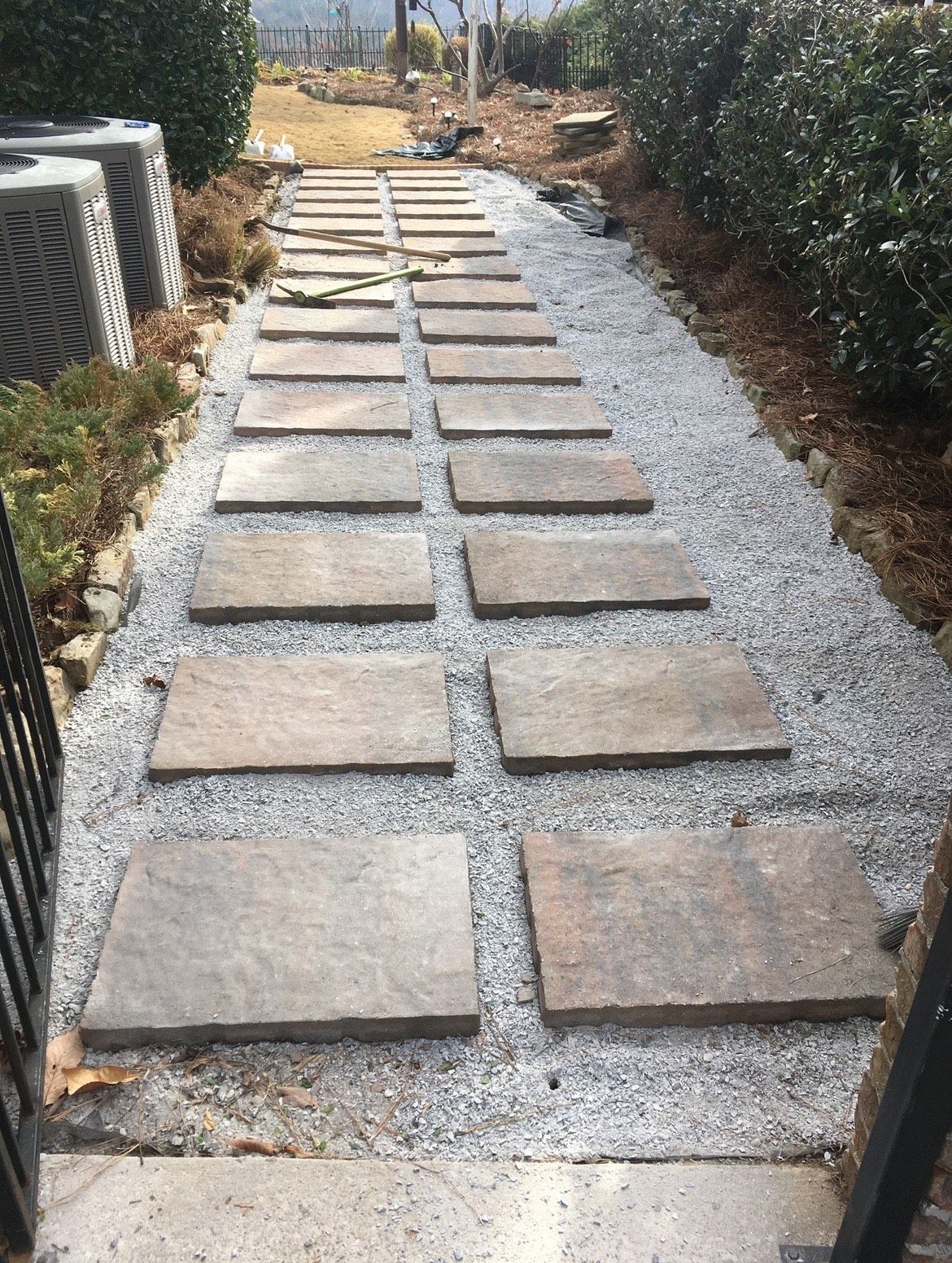 A walkway made of bricks and gravel is being built in a garden.