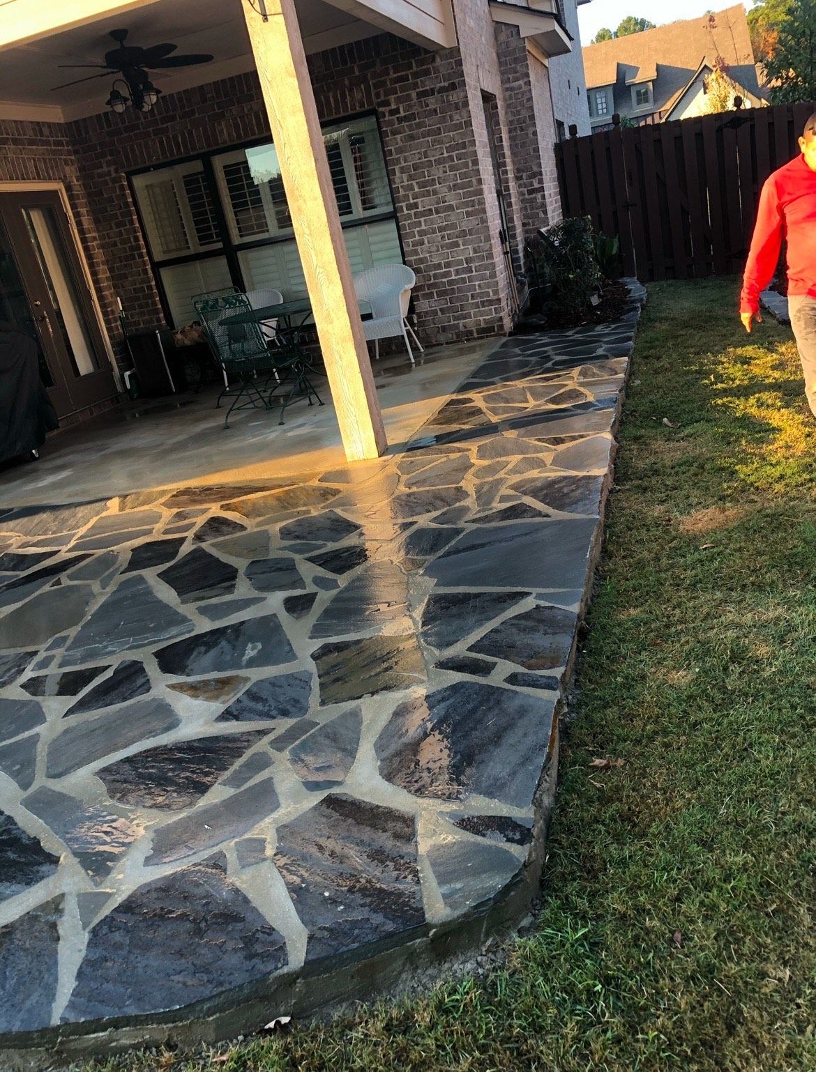 A person is walking down a stone walkway in front of a house.