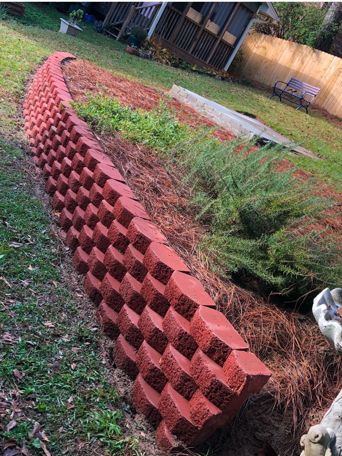 A red brick wall is sitting in the middle of a yard.