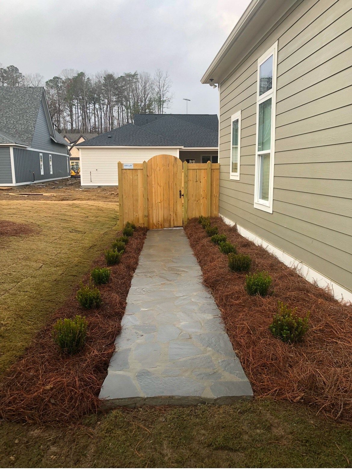 A walkway leading to a house with a wooden gate.