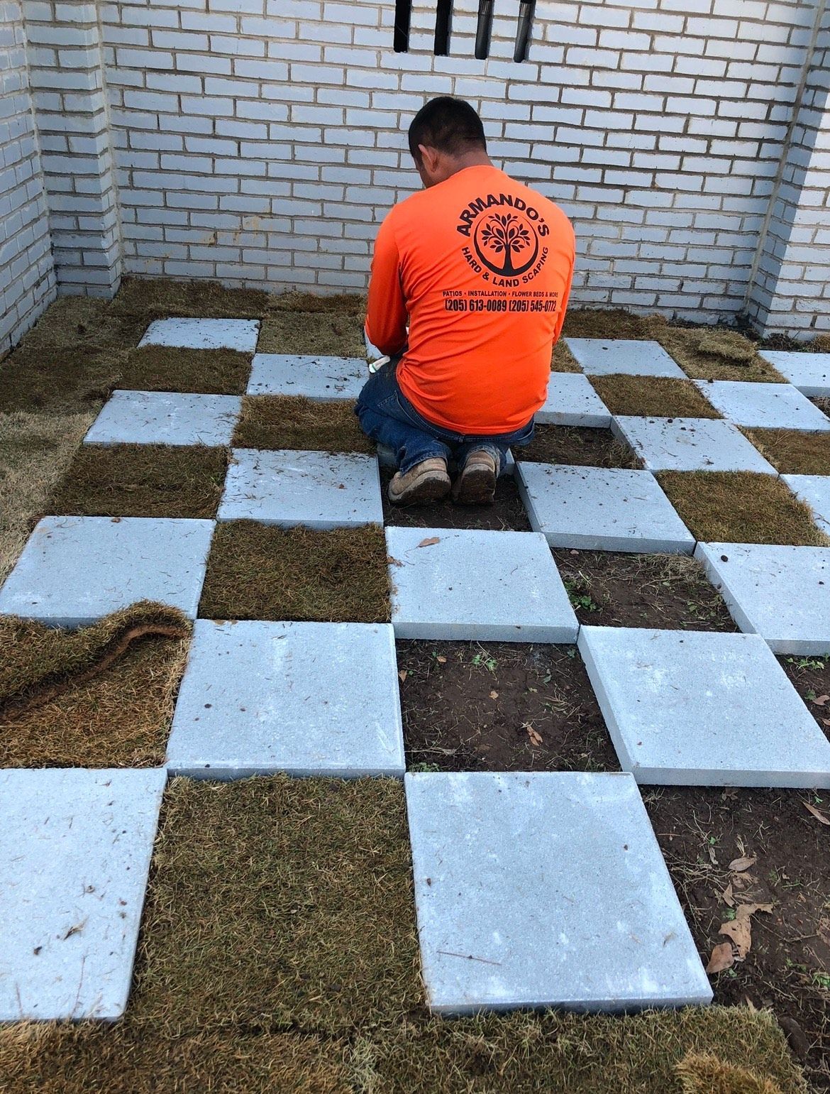 A man in an orange shirt is kneeling on a checkered floor.