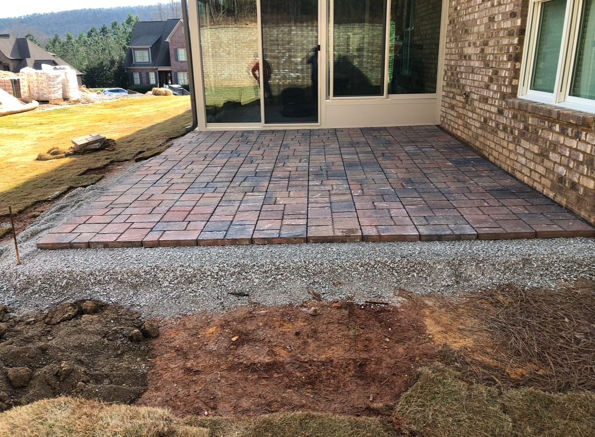 A brick patio is being built in front of a brick house.