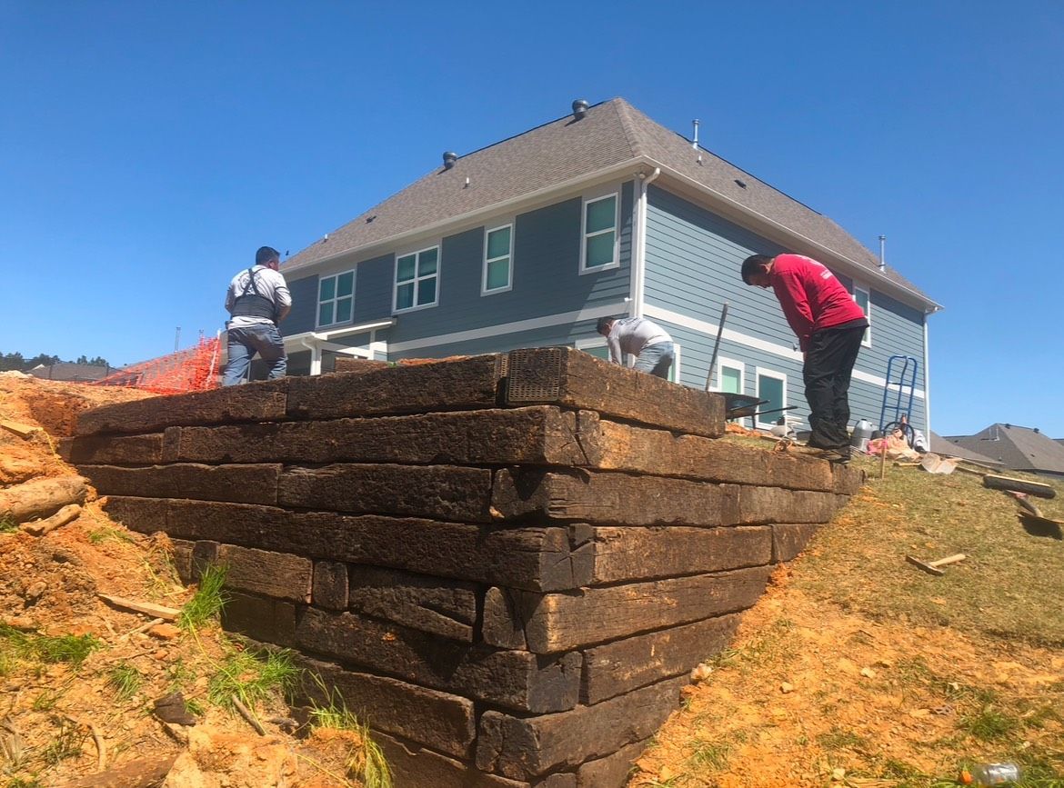 A man is standing on a brick wall in front of a large house.
