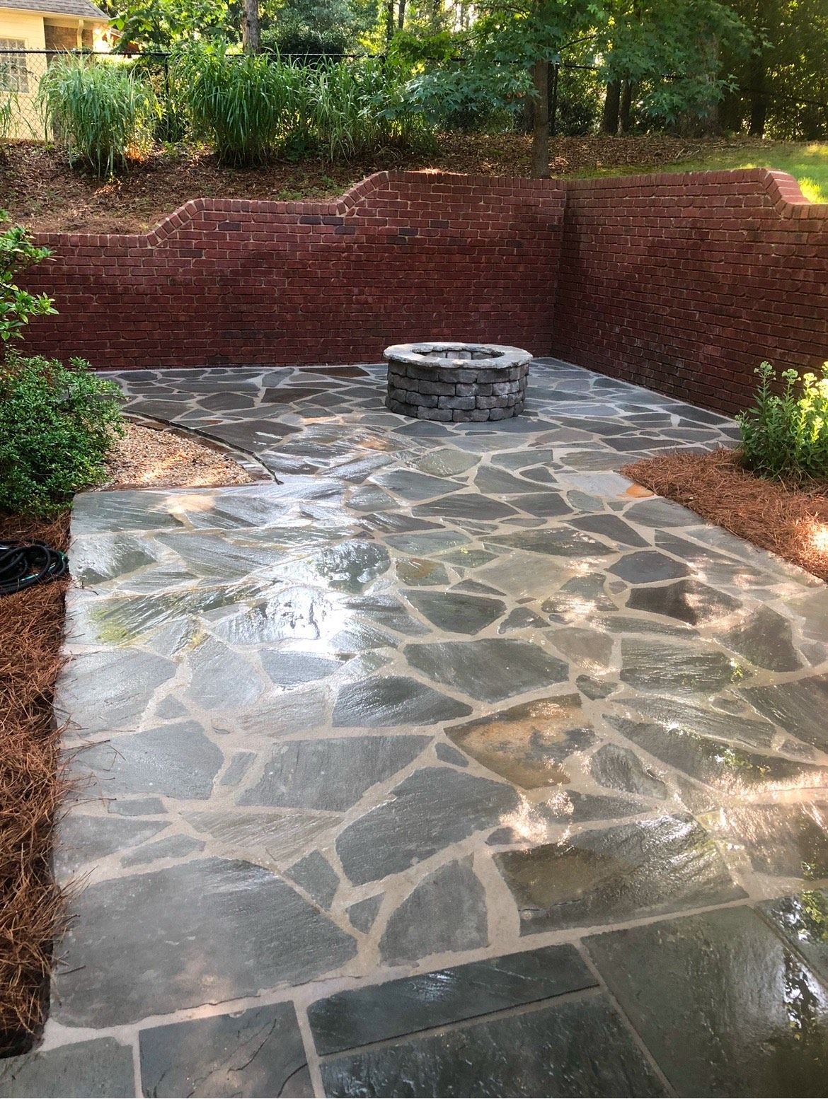 A stone patio with a fire pit in the middle of it.
