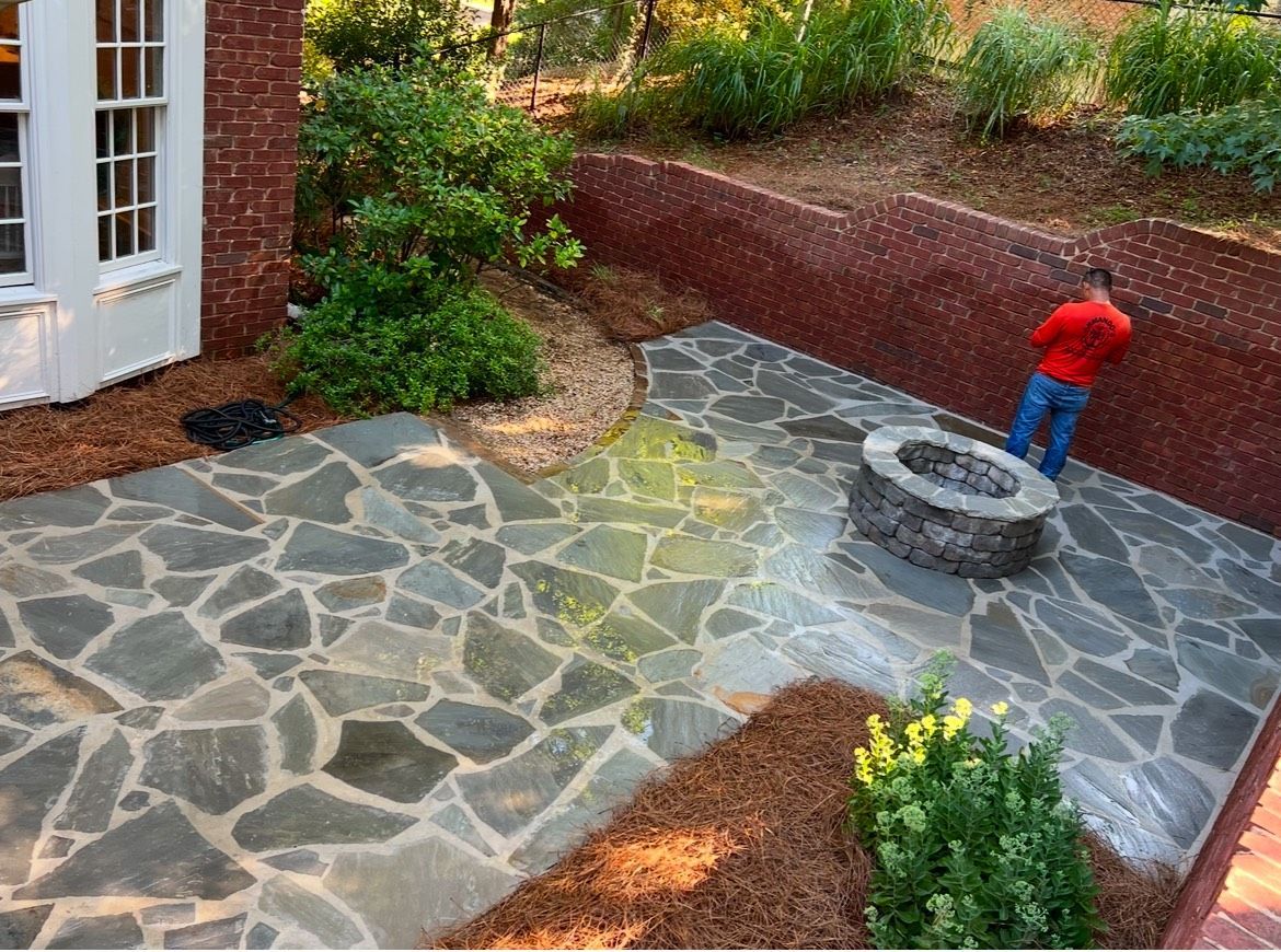 A man is standing on a stone patio next to a fire pit.