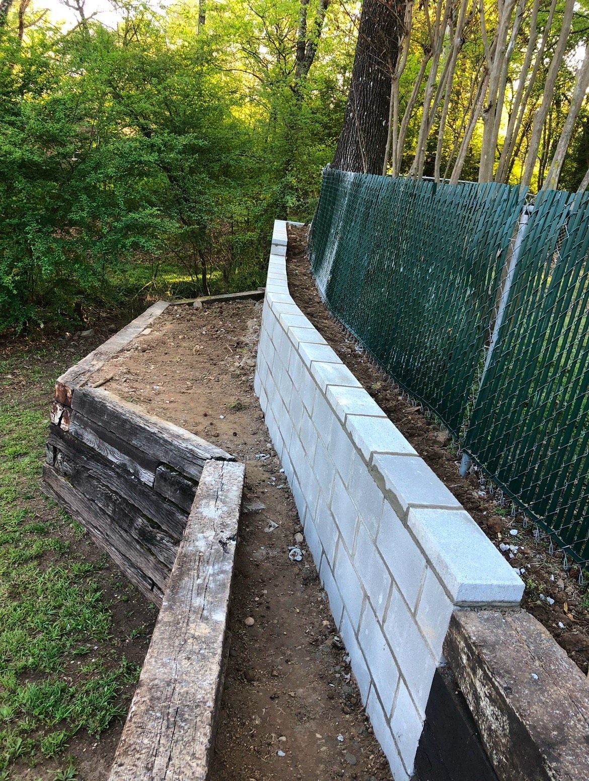 A brick wall is being built next to a chain link fence.