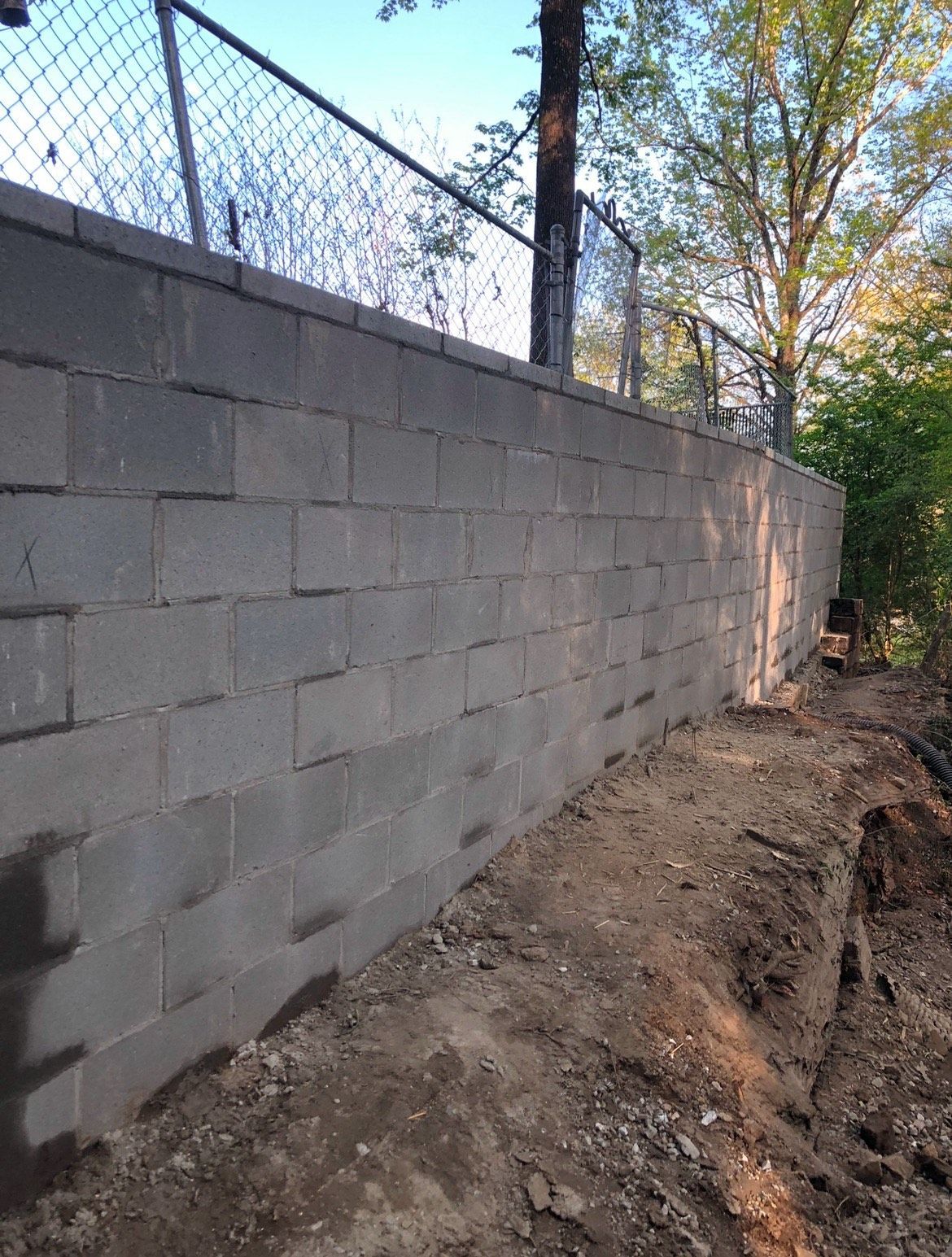 A brick wall with a chain link fence behind it